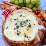 A bowl filled with cheese, grapes and bread.