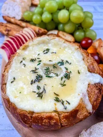 A bowl filled with cheese, grapes and bread.