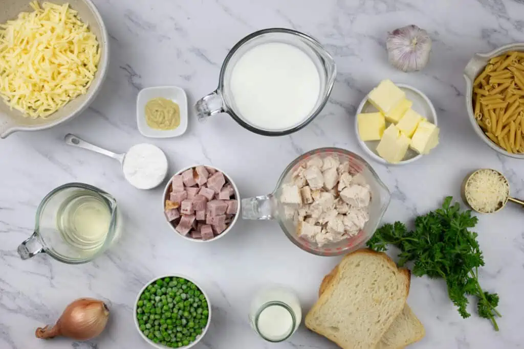 The ingredients for a pasta dish are shown on a marble table.