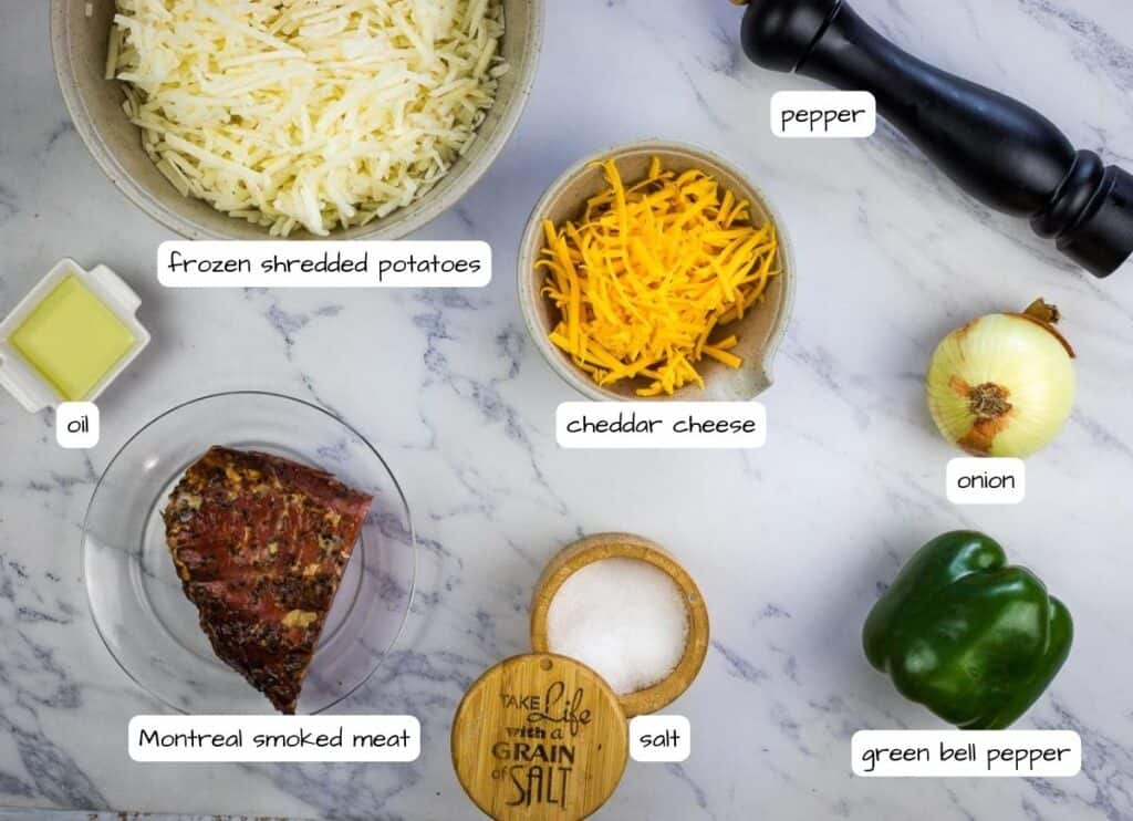 The ingredients for a cheesy steak sandwich on a marble table.