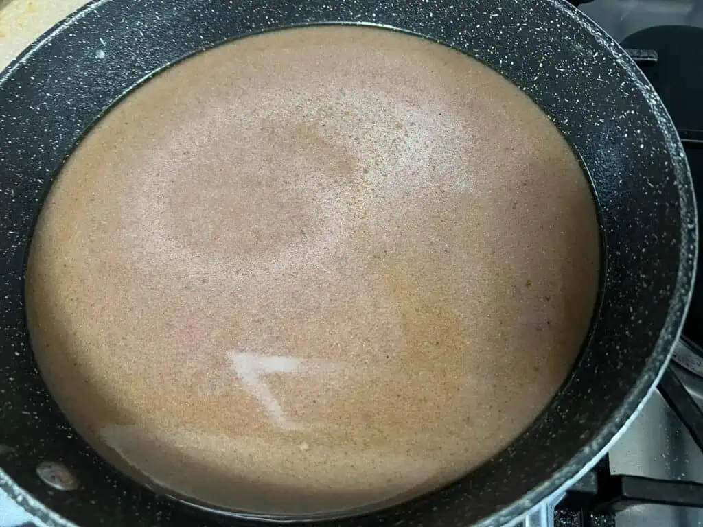 A frying pan with gravy in it.