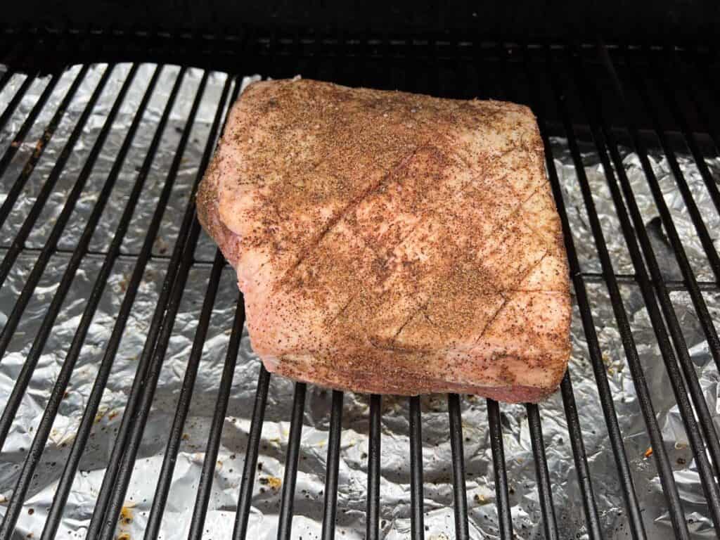 A piece of meat is being cooked on a grill.