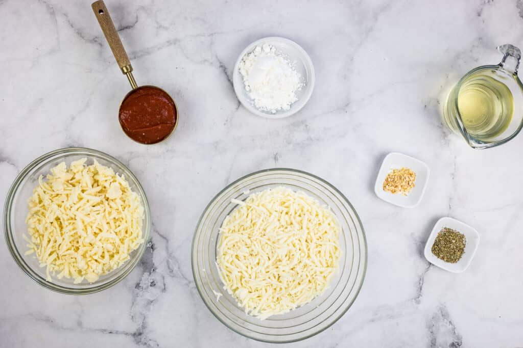 The ingredients for pizza fondue on a marble counter.