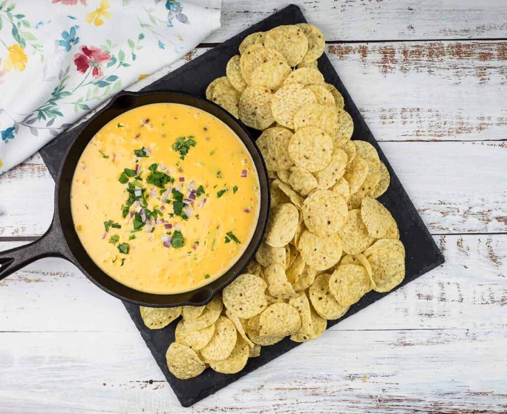 A bowl of cheesy dip with tortilla chips.