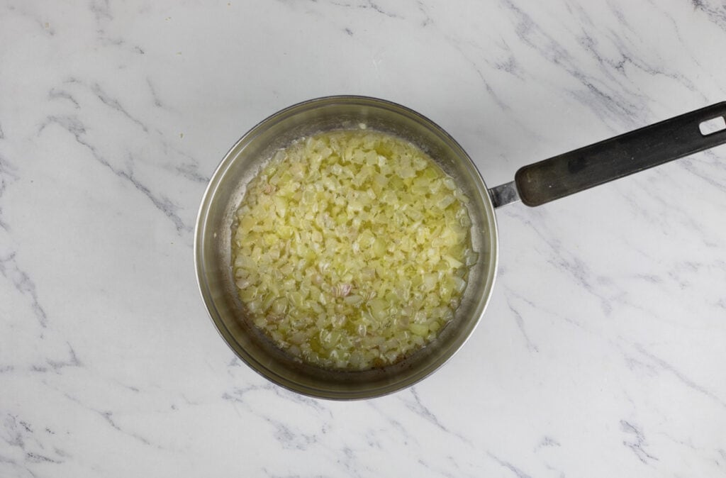 A pan with onions in it on a marble surface.