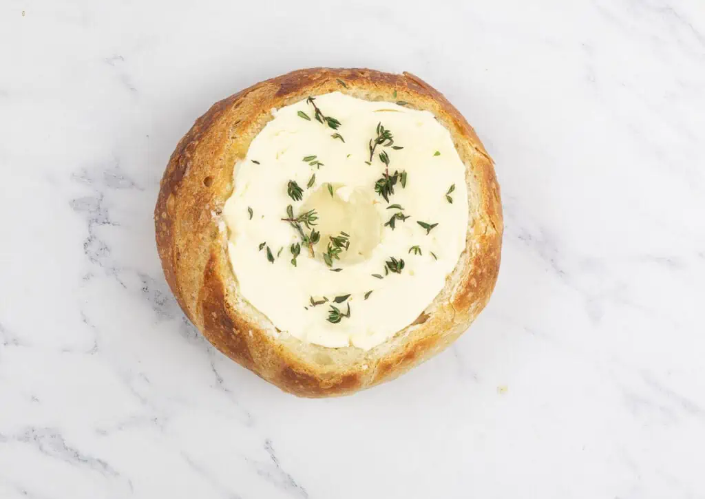 A pastry filled with butter and thyme on a marble surface.