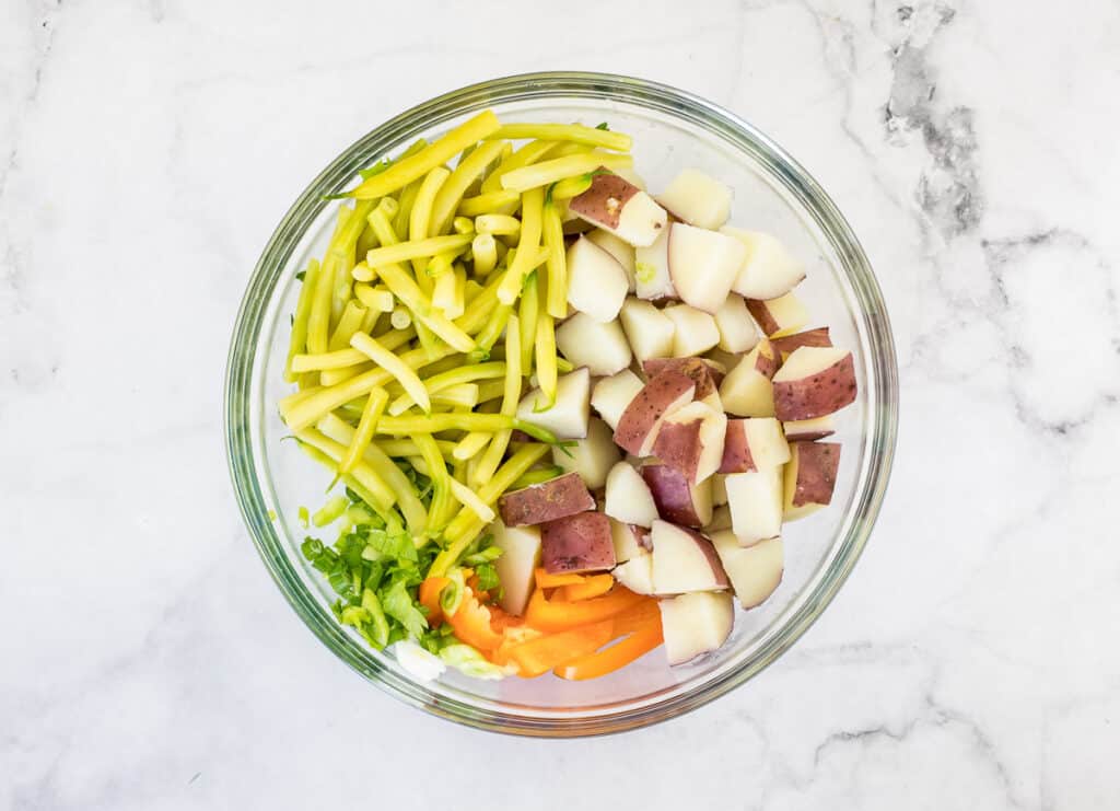 Green beans, potatoes and bell pepper in a glass bowl.