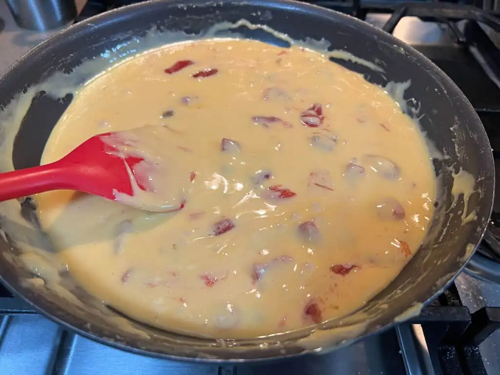 A frying pan with a red spatula in it.