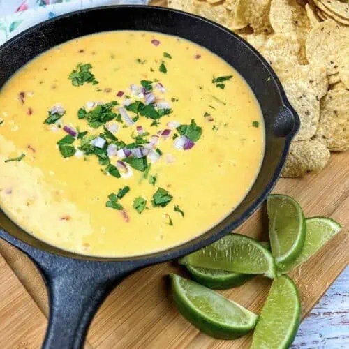 Mexican cheese dip in a cast iron skillet with tortilla chips.