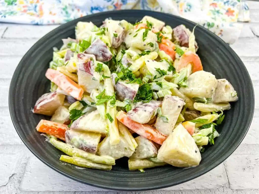 A bowl of potato salad with carrots and celery.