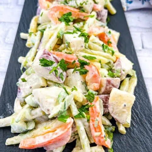 A plate of potato salad with yellow beans and parsley.