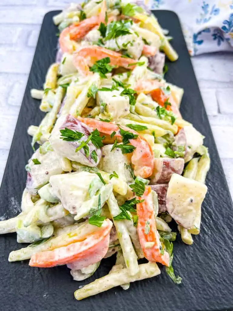 A plate of potato salad with yellow beans and parsley.