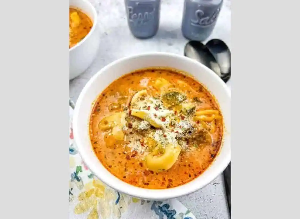 A bowl of soup with pasta and cheese.