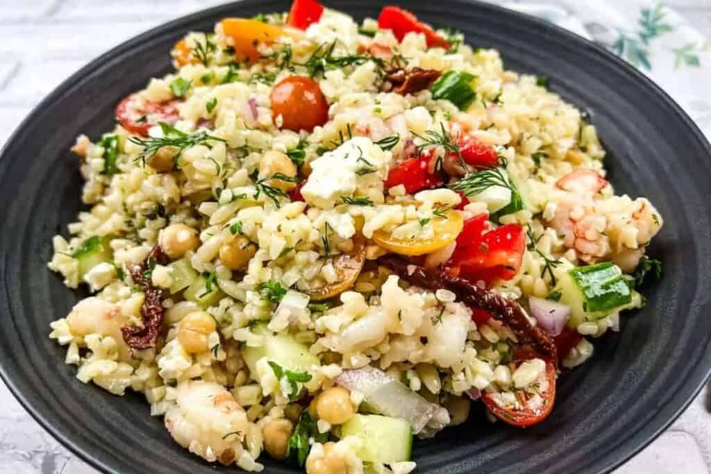 A bowl of greek salad with chickpeas and tomatoes.