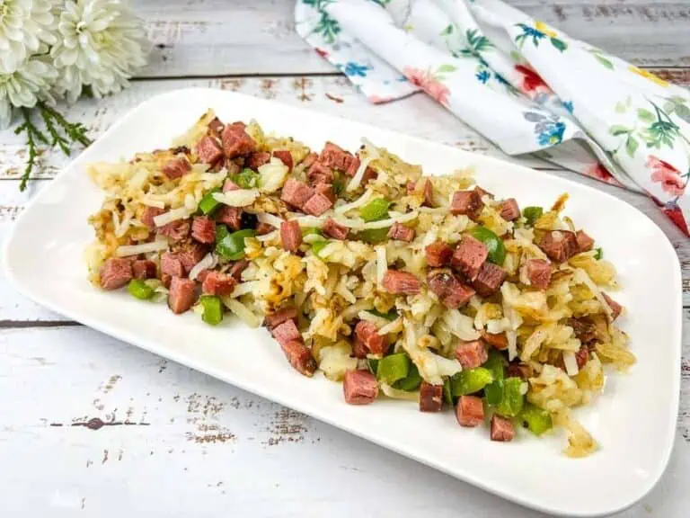 A white plate with ham and green beans on it.