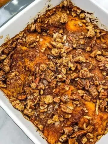 Sweet potato casserole with pecans in a white dish.