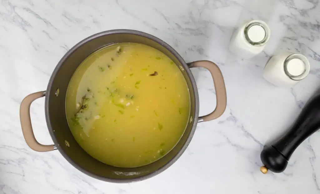 A pot of soup on a marble countertop.