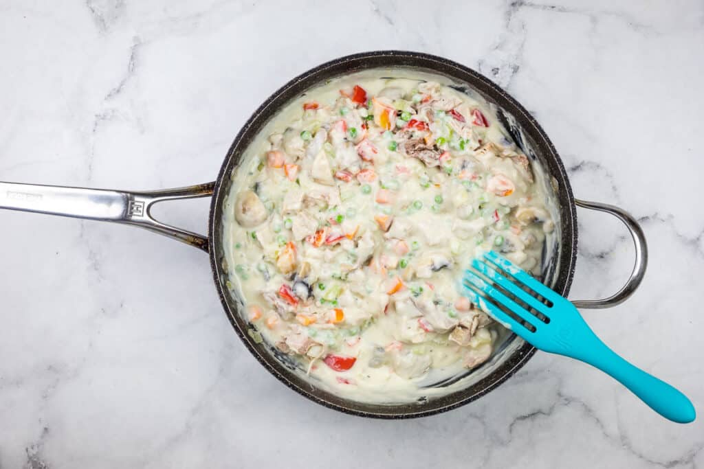 A frying pan with a blue fork in it.