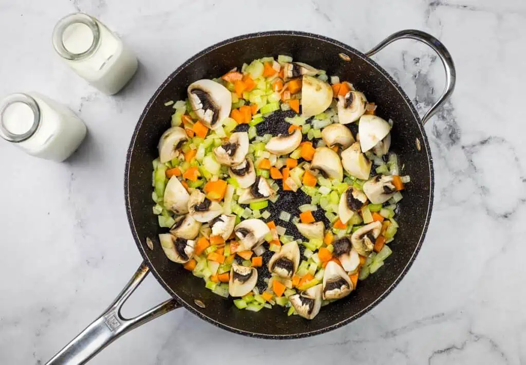 A frying pan full of vegetables and mushrooms.