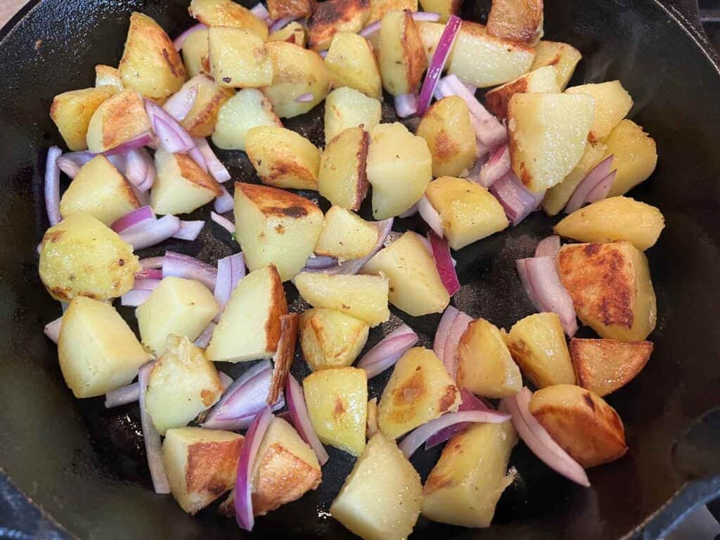 Sliced potatoes and onions in a skillet.
