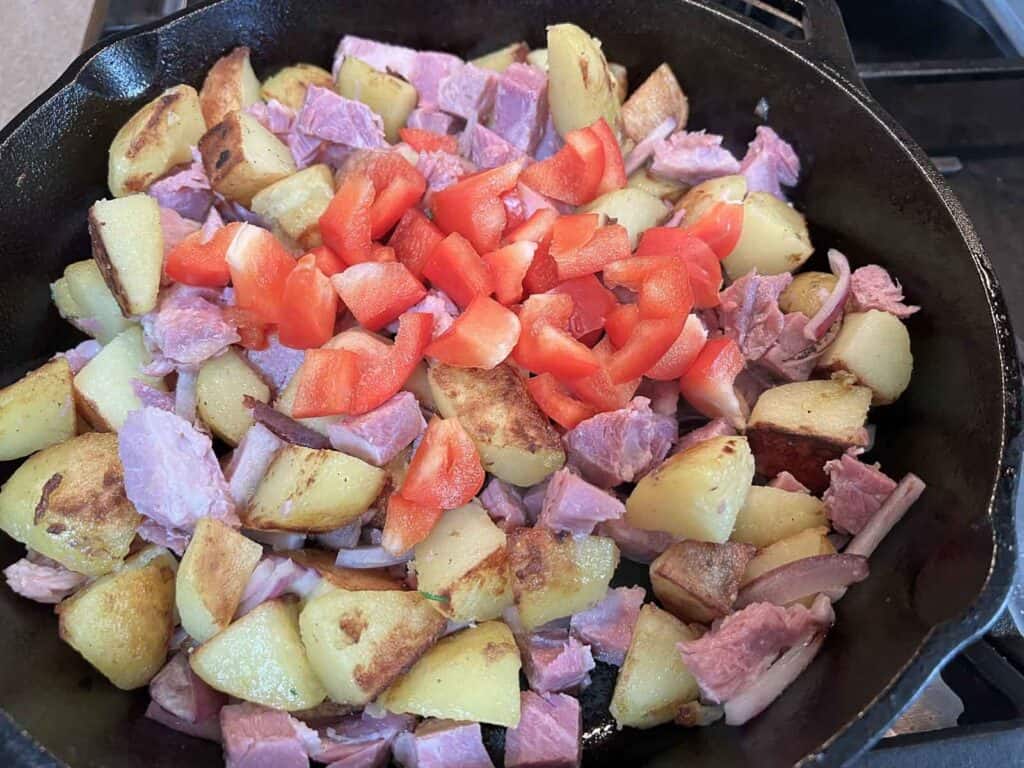 Ham, potatoes and peppers in a cast iron skillet.