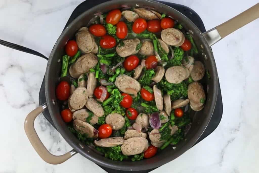 A skillet filled with vegetables and sausage.