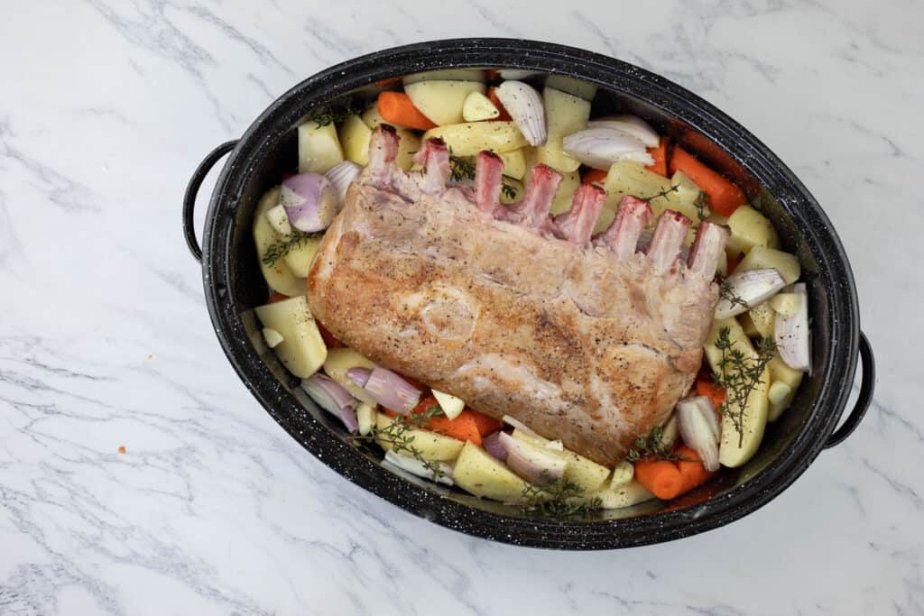 A roasting pan with vegetables and meat in it.