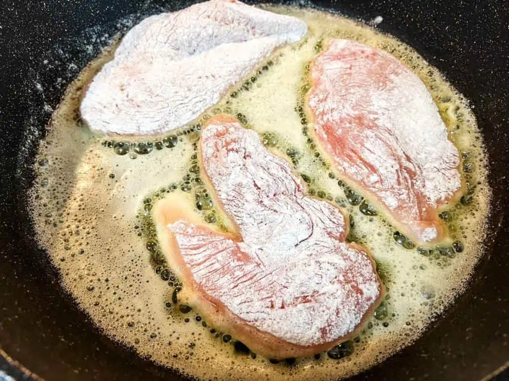 Chicken breasts being cooked in a frying pan.