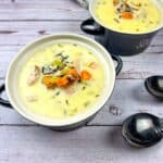 Two bowls of Creamy Chicken & Wild Rice Soup on a wooden table.