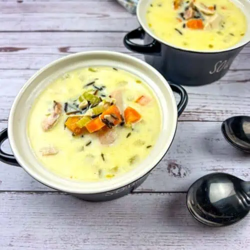 Two bowls of Creamy Chicken & Wild Rice Soup on a wooden table.