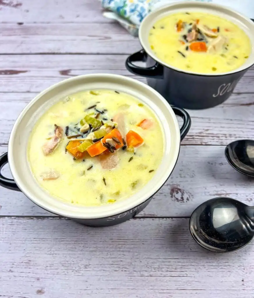 Two bowls of Creamy Chicken & Wild Rice Soup on a wooden table.