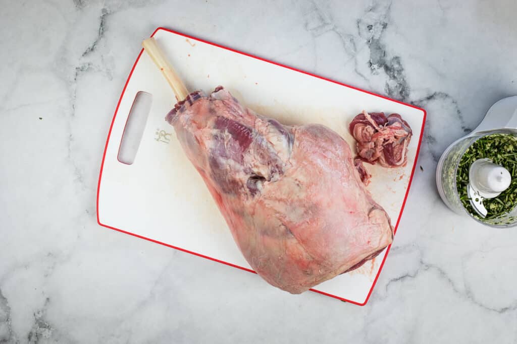 A piece of meat on a cutting board next to a blender.