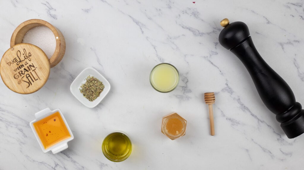 Olive oil, honey, and other ingredients are laid out on a marble table.