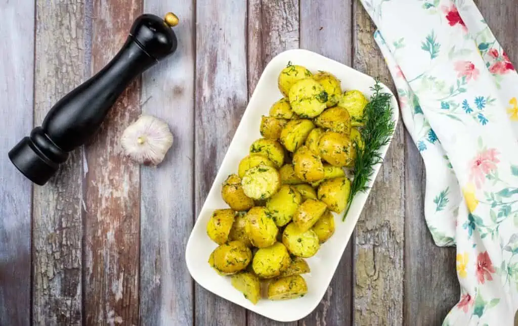Ukrainian potatoes with dill and garlic on a wooden table.