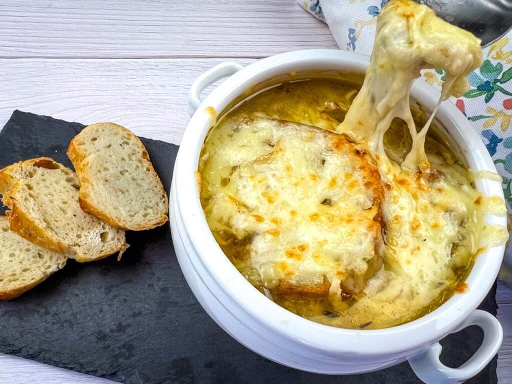 A bowl of cheesy soup with bread on top.