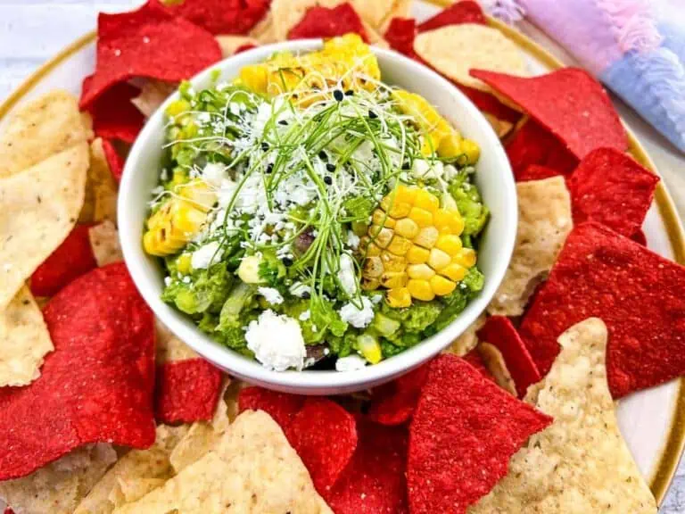 Corn guacamole on a plate with tortilla chips.
