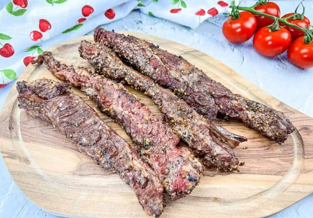 Grilled beef skewers on a wooden cutting board.