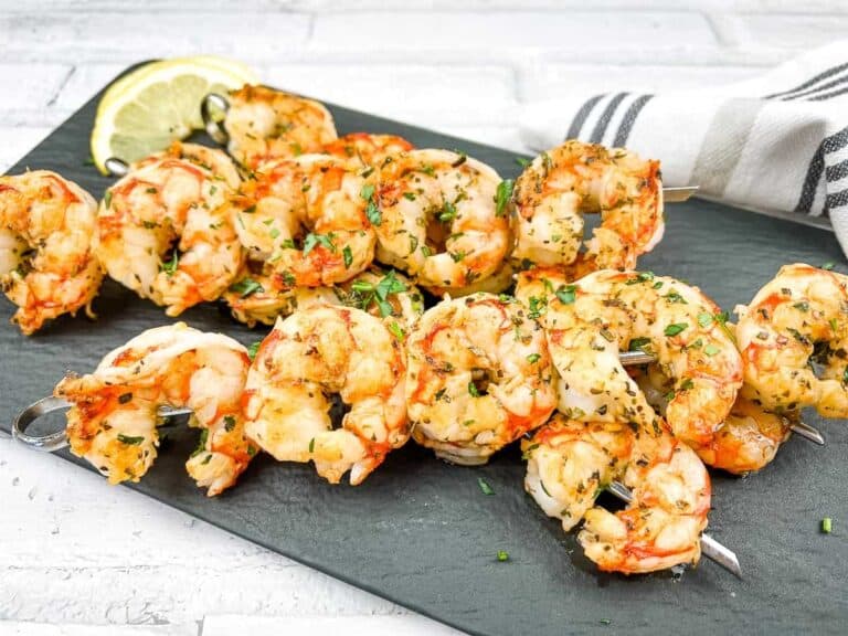 Grilled shrimp on skewers with lemon wedges.
