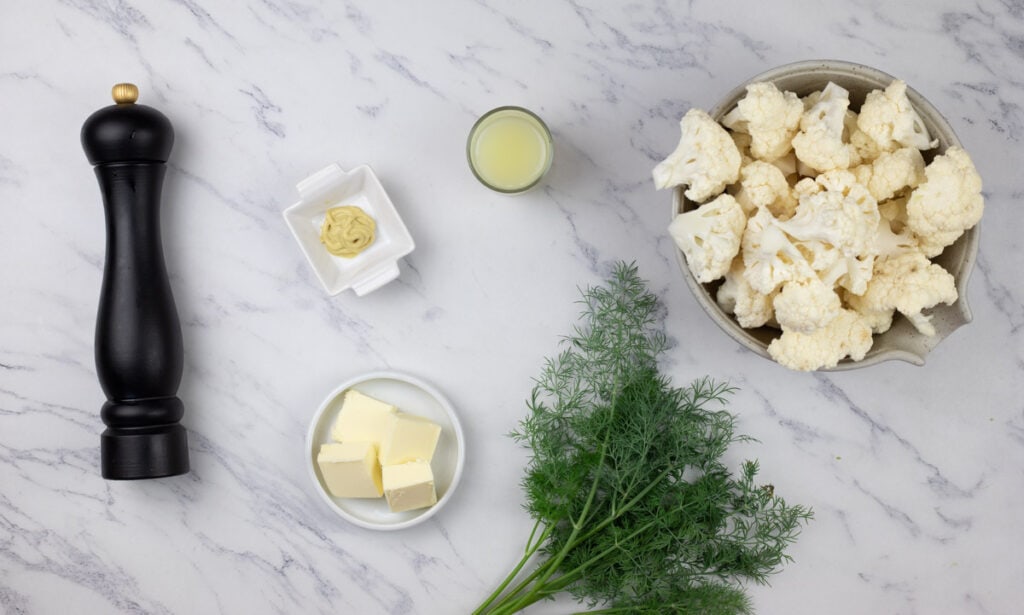 The ingredients for cauliflower with lemon and dill on a marble table.