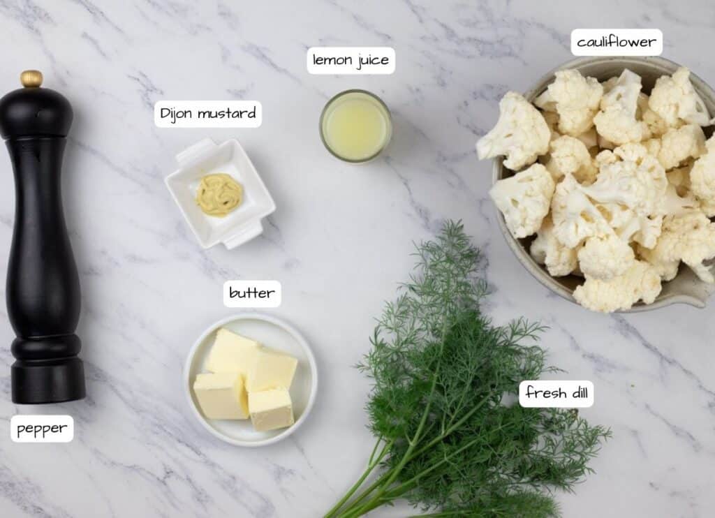 The ingredients for a cauliflower gratin are laid out on a marble table.