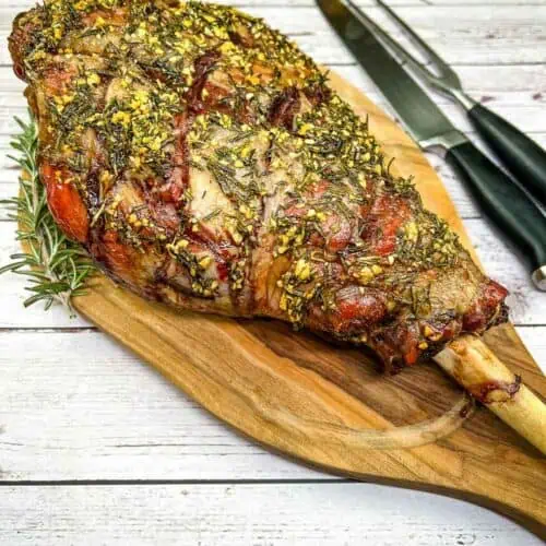 A smoked leg of lamb on a wooden cutting board.