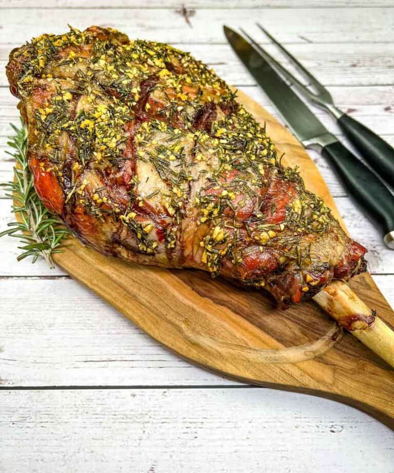 A smoked leg of lamb on a wooden cutting board.