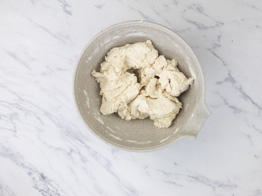Dough in a bowl on a marble surface.