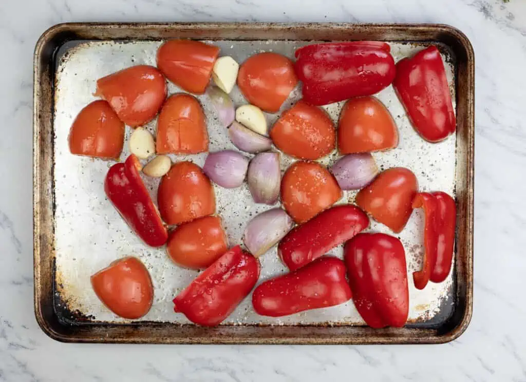 Roasted red peppers and garlic on a baking sheet.