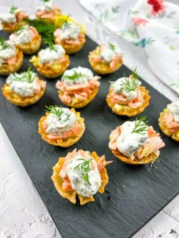 Smoked salmon tartlets with dill on a tray.