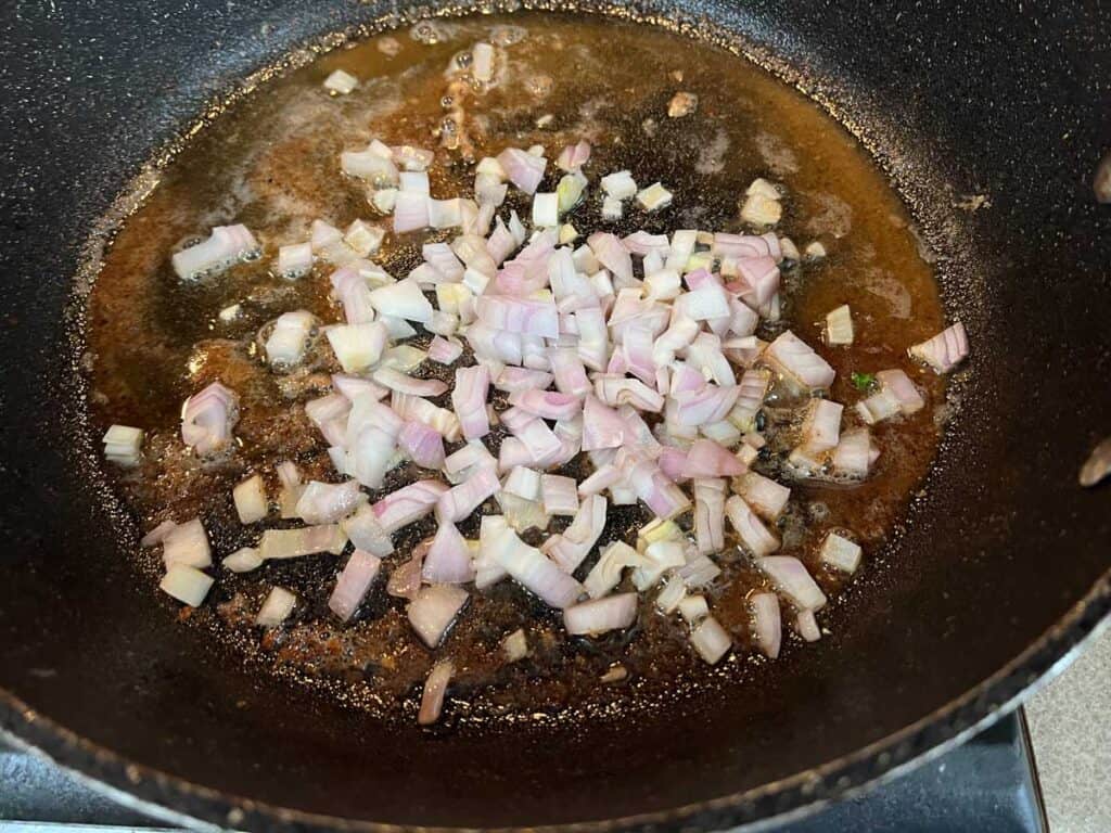 A frying pan with onions and garlic in it.