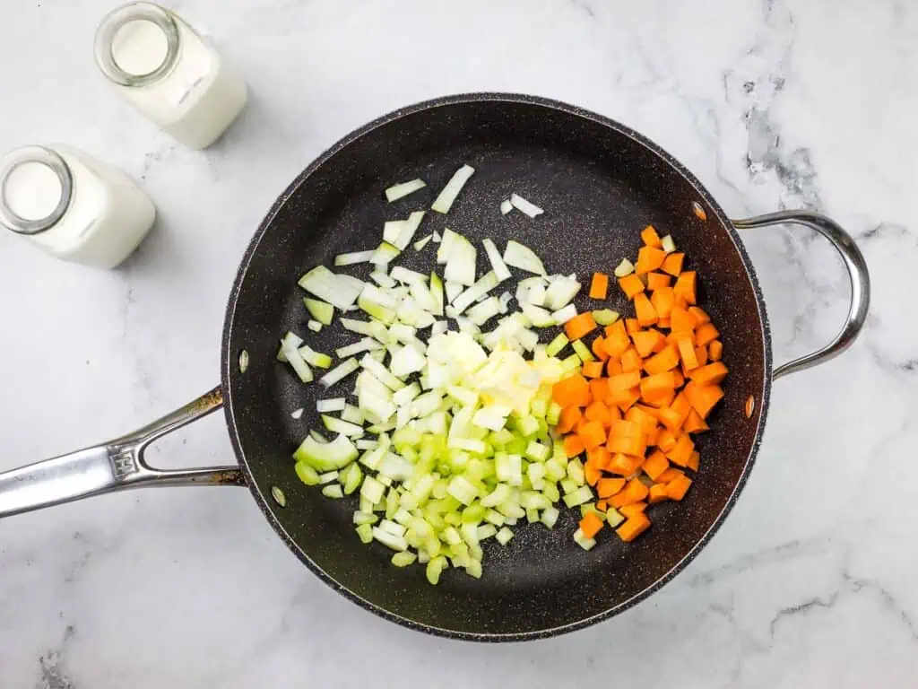 A frying pan with carrots, onions and celery.