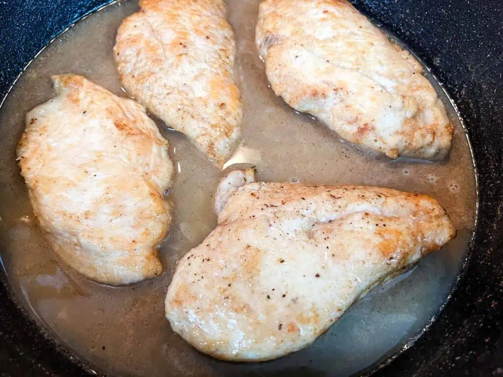 Chicken breasts in a slow cooker with gravy.