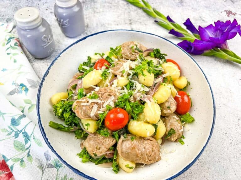 A bowl of pasta salad with meatballs and tomatoes.