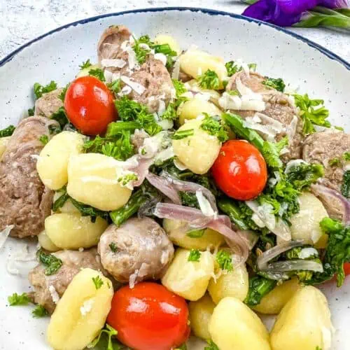 Gnocchi with sausage and tomatoes on a plate.